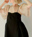 A person wearing an Arlette Top by Noémiah, featuring delicate straps and sheer, puffy sleeves, poses with arms slightly raised and head turned to the side, showcasing a short bob haircut. The elegant silk organza design stands out against the plain, light-colored background.