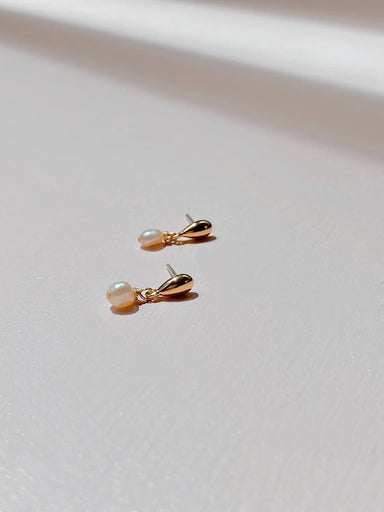 The Béatrice Earrings by Noémiah are gold-plated drop earrings adorned with small freshwater natural pearls, beautifully set against a soft, neutral background. Their delicate design catches the light, making them perfect for everyday elegance.