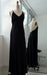The Claude Silk Satin Dress — Bridal Edit by Noémiah, a long black slip dress with thin straps, is displayed on a dress form with its front and back reflected in a large mirror by the window of a bright, modern room.