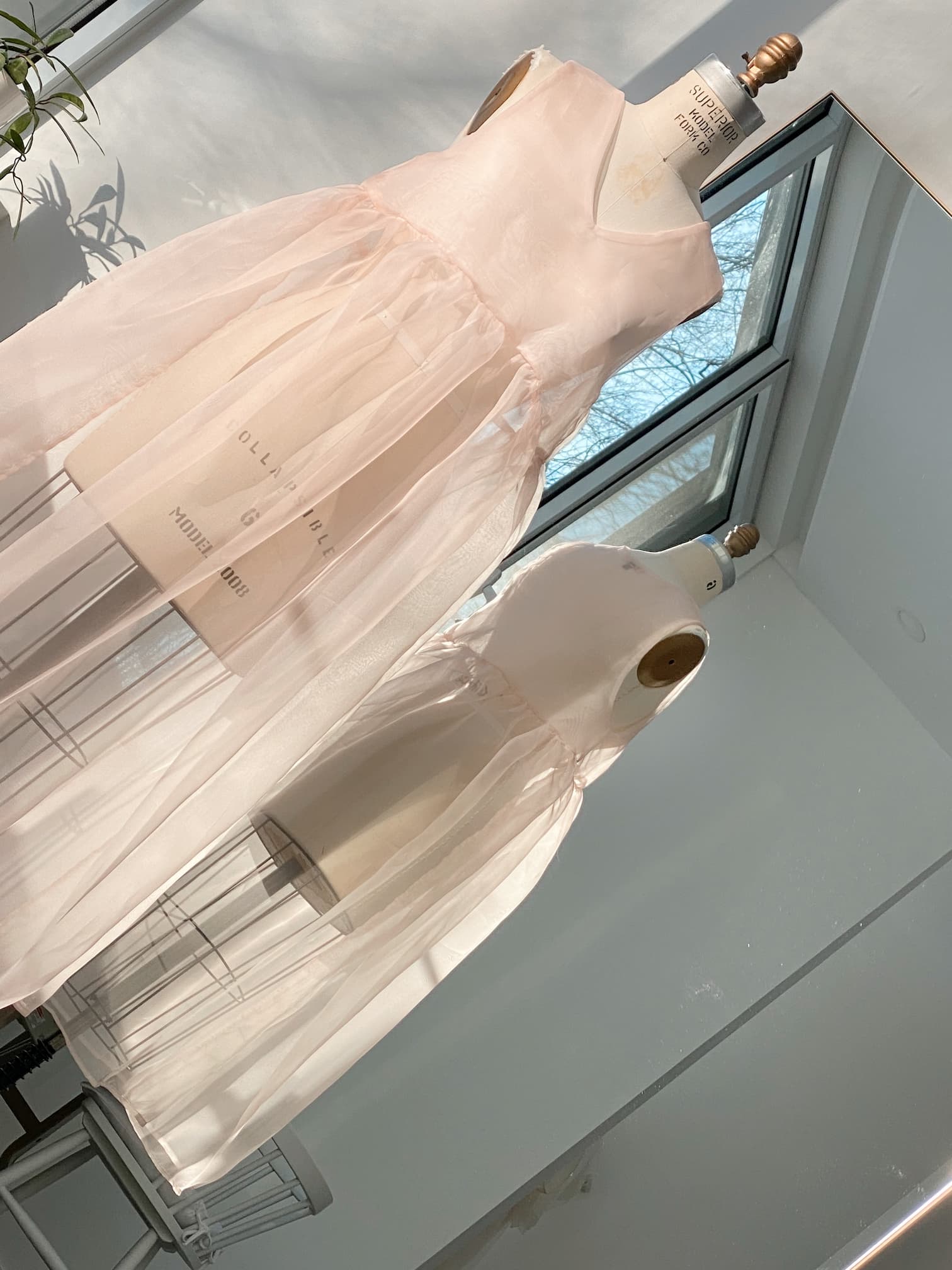 Pale pink sheer Noémiah Coco silk dress on a mannequin, displayed in a studio setting.