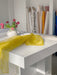 A bright, minimalistic room is filled with inspiration as vibrant rolls of fabric stand behind a sheer yellow organza silk drape, evoking the elegant Esperanza Midi Dress by Noémiah—perfect for imagining dresses with puffed sleeves.
