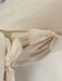 Close-up of beige fabric with decorative bows tied along the edges, achieving a soft and elegant look reminiscent of the Noémiah Esperanza Midi Dress in raw silk.