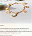 The Jane Bracelet by Noémiah showcases delicate gold-plated charms—a crescent moon, heart, flower, and star—each adorned with Swarovski crystals and beautifully presented against a beige background.