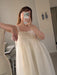 A person takes a mirror selfie wearing the Noémiah Jeanne Dress — Bridal Edit, a white, sleeveless, sheer-layered silk organza dress with a square neckline and scalloped trim.