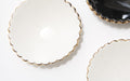 Displayed are three decorative ceramic pieces from Noémiah's Jewelry Dish collection. Perfect for use as side plates or jewelry holders, these handmade dishes feature scalloped edges and elegant gold rims. Two dishes are white with a subtle speckled pattern, while the third is black, all beautifully arranged on a white surface.