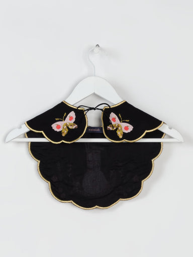 The Olivia Black Collar — Snail on the Back by Noémiah is elegantly showcased on a white hanger. It highlights delicate embroidered pink and gold butterflies on each side and features a scalloped edge with a ribbon tie at the front, making it an enchanting accessory for any ensemble.