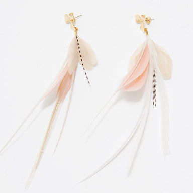 A pair of Pénélope Earrings by Noémiah, showcasing long, flowing feathers in soft shades of pink, cream, and white. These earrings are complemented by gold-toned bead accents and feature tarnish-resistant plating to maintain their stunning appearance. Displayed against a plain white background.