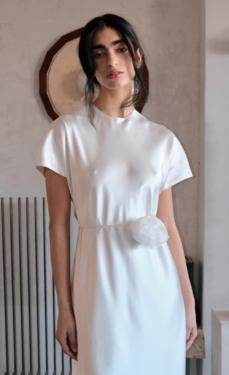 A woman with long dark hair wears the Noémiah Silk Belt, accentuating her silhouette, styled indoors against a neutral background.