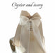 Noémiah Silk Ribbon: An elegant ivory and oyster silk bow with scalloped, embroidered edges and sheer organza ribbons cascading down—a delicate accessory for any occasion.
