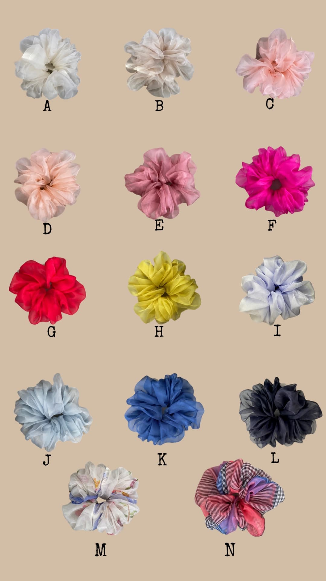 A set of 14 scrunchies, crafted from Noémiah's Tulip Dress scraps and made entirely of silk organza, is displayed in a grid against a beige background. Each scrunchie, labeled A through N, features a diverse array of colors and patterns, from neutral tones to vibrant designs.