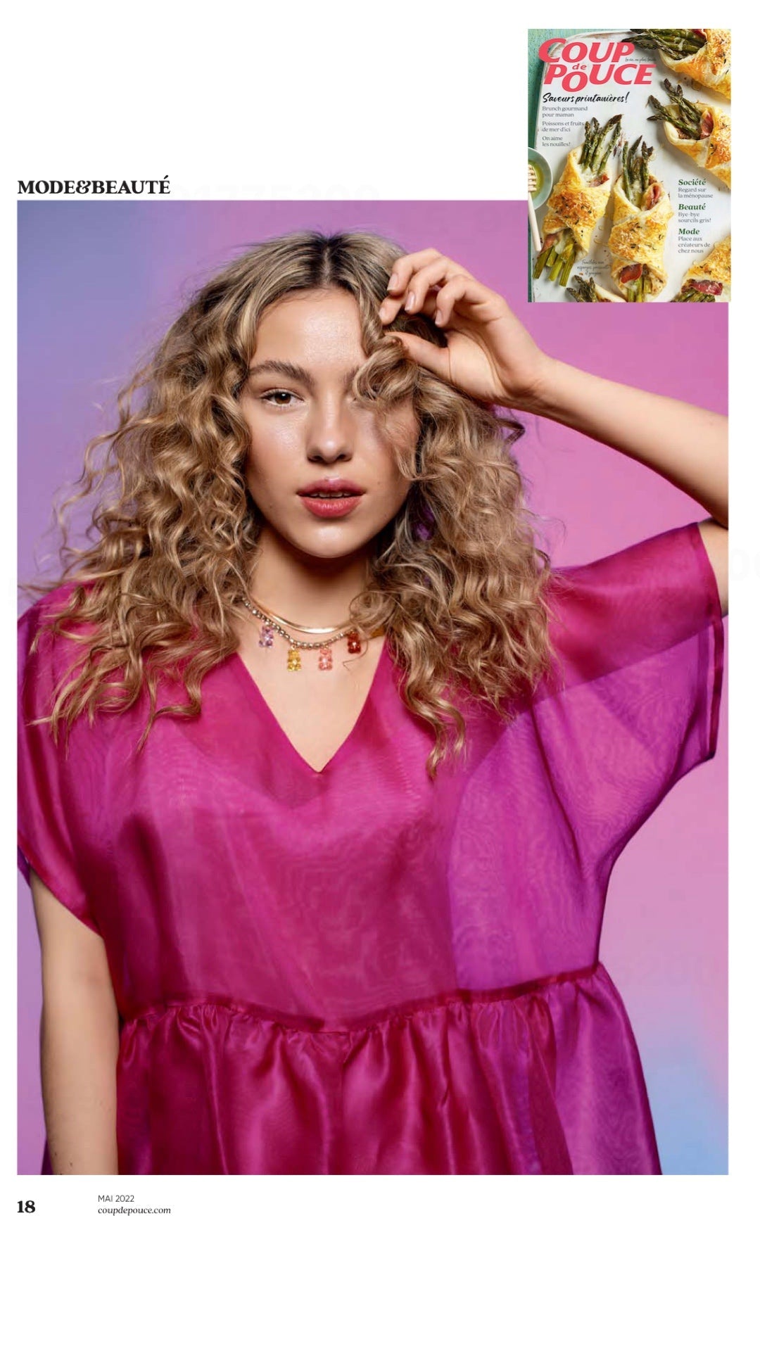 A woman with curly blonde hair poses against a pink and purple gradient background, showcasing the noemiah Tulip Dress in relaxed fit, crafted from sheer bright pink silk organza, complemented by layered necklaces. A small image of food appears in the top right corner.