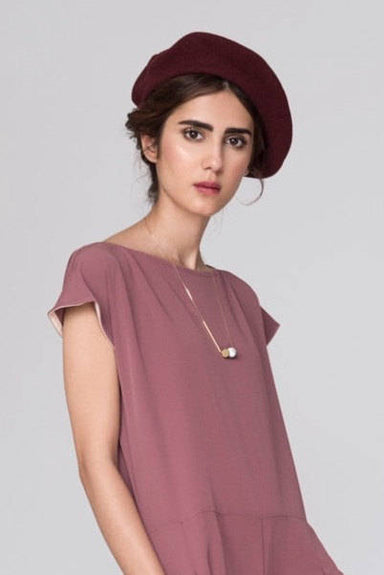 A person wearing a mauve dress and a burgundy beret stands against a neutral background. Their shoulder-length hair complements the Urso Necklace by noemiah, featuring tarnish-resistant plating that enhances its minimalist design.