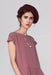 A person wearing a mauve dress and a burgundy beret stands against a neutral background. Their shoulder-length hair complements the Urso Necklace by noemiah, featuring tarnish-resistant plating that enhances its minimalist design.