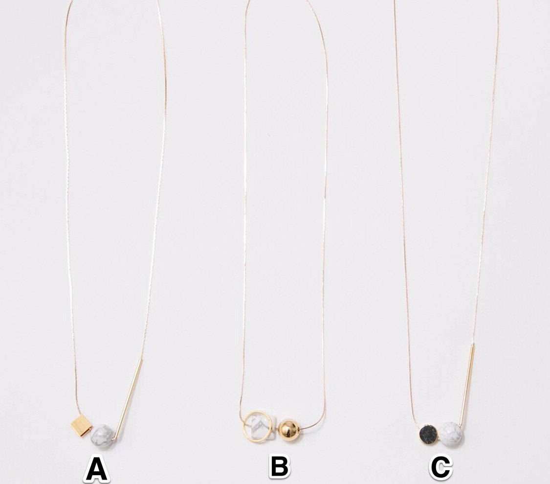 Three minimalist necklaces from noemiah's Urso Necklace collection include options A, B, and C. Necklace A features a cube and spherical pendant; Necklace B highlights two spherical pendants; and Necklace C presents a cylindrical rod alongside a circular pendant. Each necklace is set on a delicate chain with tarnish-resistant plating to ensure lasting shine.