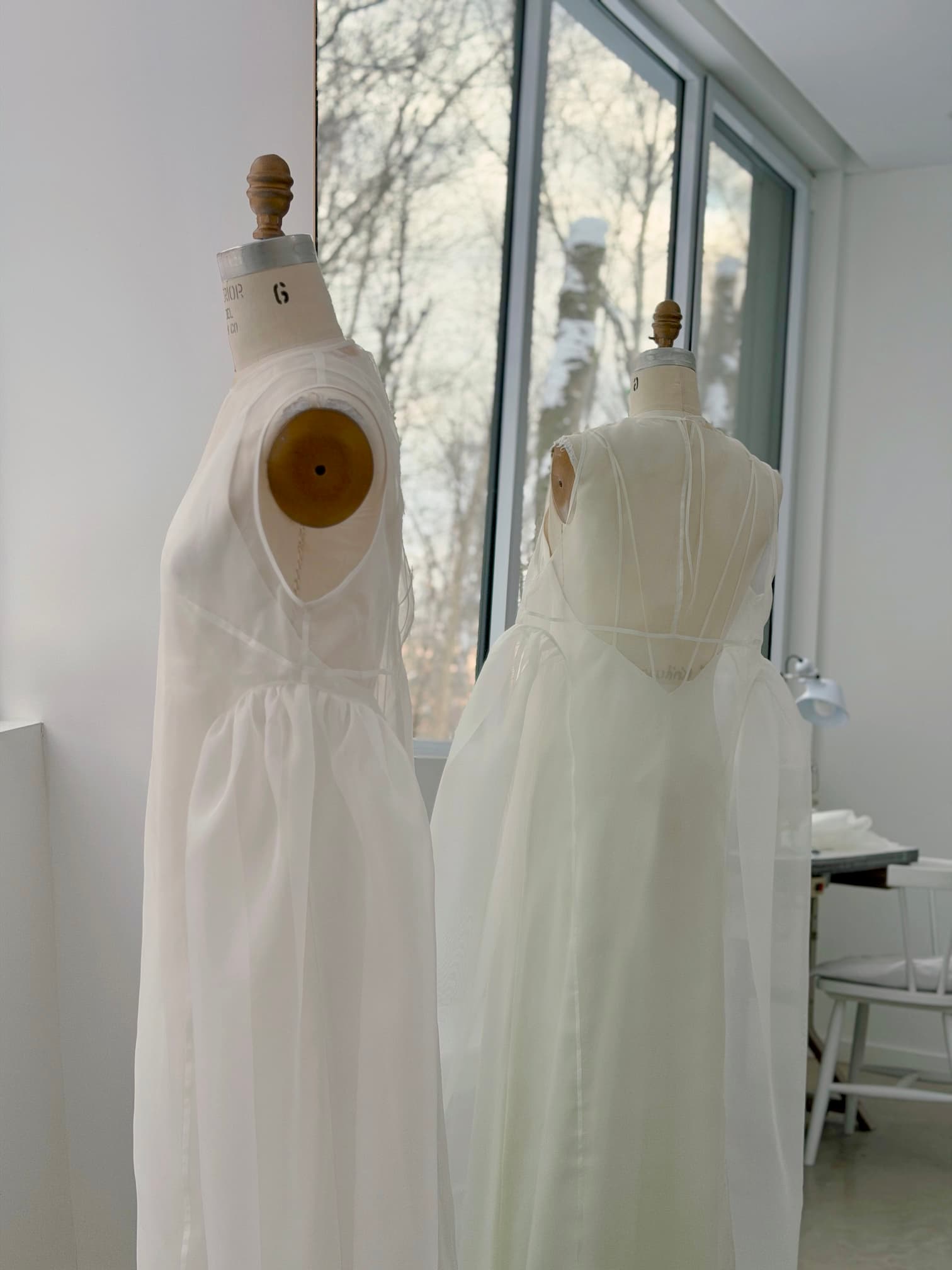Deux robes Noémiah Vivi en organza de soie transparent, présentées sur des mannequins de couture dans un décor de studio.